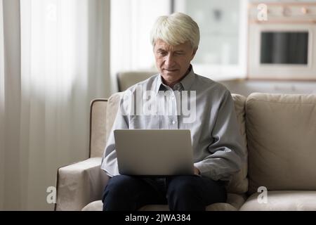 Focused mature freelance businessman working at home, typing on laptop Stock Photo