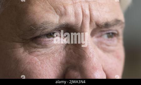 Brown eyes of serious older grey man looking away Stock Photo
