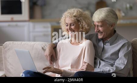 Happy romantic mature couple relaxing on home couch together Stock Photo