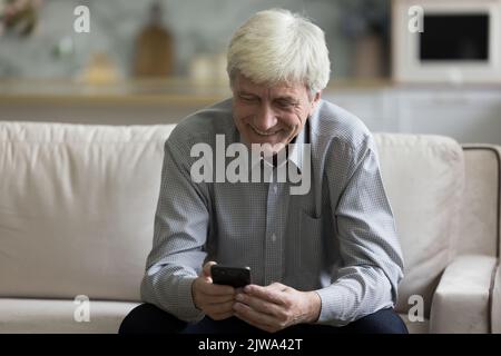Happy engaged old retired man chatting on mobile phone Stock Photo