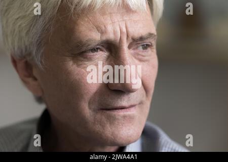 Thoughtful concerned senior old man face close up cropped shot Stock Photo