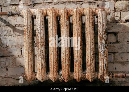 A rusty cast-iron battery in a burnt-out house. Cast iron battery. Heating device. The place of the fire. Burnt apartment. Conflagration place. Seat o Stock Photo