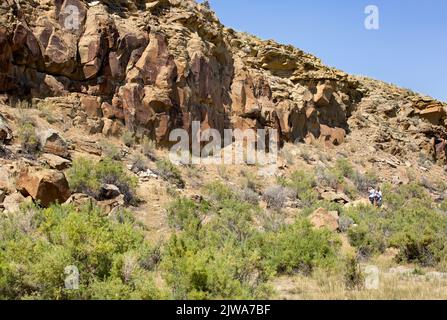 Tourists viewing historic Native American petroglyphs rock art on sandstone panels in Legend Rock State Archaeological Site, Wyoming Stock Photo