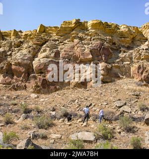 Tourists viewing historic Native American petroglyphs rock art on sandstone panels in Legend Rock State Archaeological Site, Wyoming Stock Photo