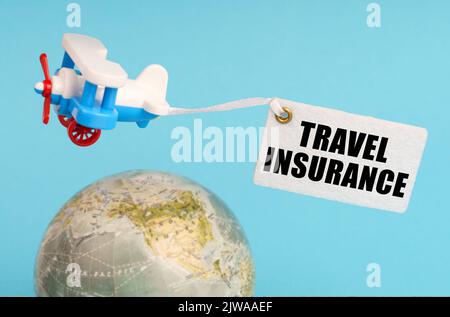 Travel and business concept. On a blue background, a globe and an airplane with a sign - Travel Insurance. Globe out of focus. Stock Photo