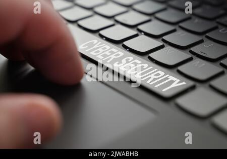 On the laptop keyboard of a person's hand, on the space bar there is an inscription - Cyber security Stock Photo