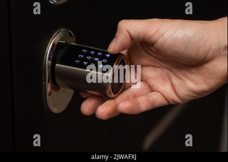 Woman opens the combination lock on the door to the apartment. Keyless entry.  Stock Photo