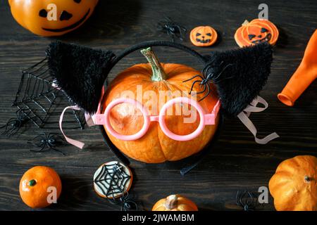 Halloween still life on wooden table, pumpkins and sweets on dark wood. Happy orange pumpkin with glasses, variety Halloween food and decorations. Lif Stock Photo