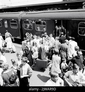 Image of crowds with train travelers when entering and getting out at the electric train set no. 263 (Mat. 1946) of the N.S. ('Valkenburg Expres') at the N.S. station Valkenburg. Stock Photo