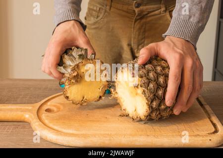 Man checking a pineapple's freshness on a wooden table. Concept of healthy lifstyle, vegeterian food. Copy space Stock Photo