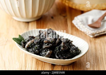 Tumis Cumi Hitam or Stir Fry Squid in Black Ink Sauce. Indonesian Traditional Food Made from Squid with Spicy Seasoning. Close Up Stock Photo