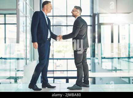 Lets shake on it. two businessmen shaking hands together in an office. Stock Photo