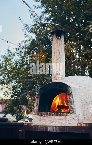 Wood-fired pizza oven with birch logs for kindling. The fire burns and the  oven heats up. Front view Stock Photo - Alamy