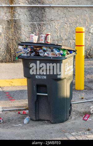 A Noble County Disposal trash can overflowing with garbage. Stock Photo