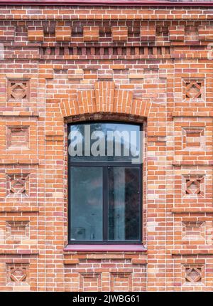 The window of the old mansion 19 century with brown bricks wall. Brick wall of an old 19th century building with large window. Stock Photo