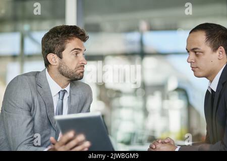 Ensuring their companys success. two colleagues lusing a digital tablet together in an office. Stock Photo