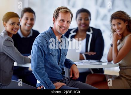 Working with the best is always reason to smile. Portrait of a group of smiling colleagues sitting in an office. Stock Photo