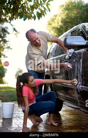 Making sure they dont miss a speck of dirt. a father and daughter washing a car together outside. Stock Photo