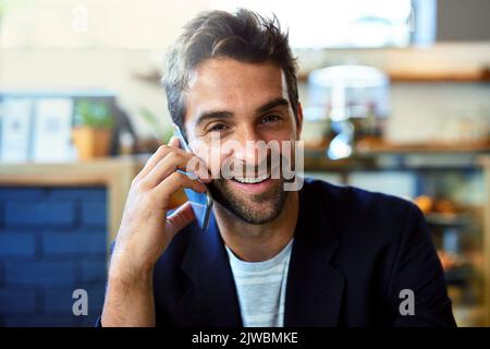 Success and smiles all around. Portrait of a handsome young man talking on a phone in a cafe. Stock Photo