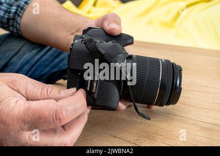Male photographer inserting a flash memory card while holding a professional camera. Stock Photo