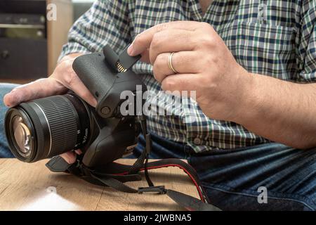 Male photographer inserting a flash memory card while holding a professional camera. Stock Photo