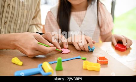 cropped and close-up, Happy and kind male art teacher teaching and showing how to moulding colorful clay in a different shapes. Stock Photo