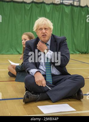 File photo dated 26/08/2020 of Prime Minister Boris Johnson with Olivia Stokes in the gym taking part in a getting to know you induction session with year sevens as he tours Castle Rock school, Coalville, in the east Midlands. Either Liz Truss or Rishi Sunak will be declared as the new leader of the Conservative Party, and successor to Prime Minister Boris Johnson, on Monday afternoon. The incoming PM will face a daunting set of challenges including an energy crisis, soaring inflation, further strike action and the ongoing war in Ukraine.Issue date: Monday September 5, 2022. Stock Photo