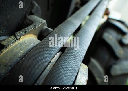 Two thick belts on the engine close-up. Drive belt old worn out on a yellow pulley, blurred background. Industrial items in agriculture Stock Photo