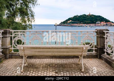 A bench overlooking Paseo de la Concha promenade and La Concha bay and Monte Urgull in San Sebastian, Spain