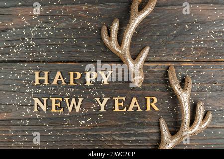 Happy new year greeting card with wooden text and golden raindeer horns. Festive background Stock Photo