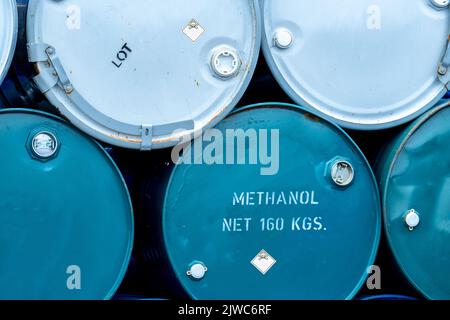 Old chemical barrels. Stack of blue methanol or methyl alcohol drum. Steel chemical tank. Toxic waste. Chemical barrel with toxic warning symbol. Stock Photo