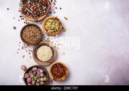 Top view of mix bright spices or seasonings in small wooden bowls as ingredient for healthy food on grey concrete background Stock Photo