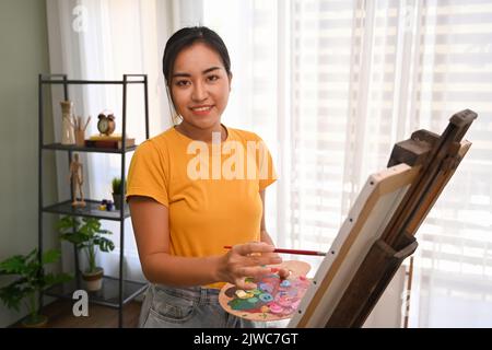 Female artist painting picture with watercolor in bright daylight studio. Art, creative hobby and leisure activity concept Stock Photo