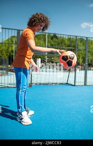 Active teenager basketball player practicing with ball on street court ...