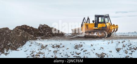 Bulldozer working on road construction site in grading phase in winter time, copy space included Stock Photo