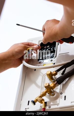 Professional male technician repairing modern air conditioner outdoors. Close up of man checking, repairing or installing outdoor air conditioner unit Stock Photo