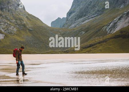 Man hiking solo in Norway travel adventure vacations outdoor active healthy lifestyle tourist backpacking on sandy Horseid beach Lofoten islands Stock Photo