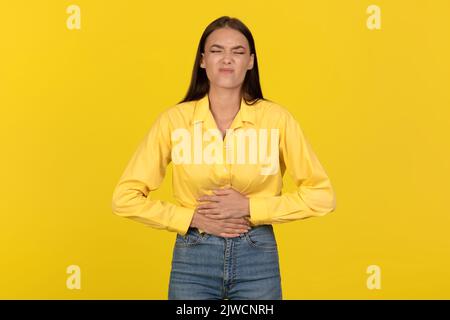 Lady Touching Aching Belly Suffering From Pain Over Yellow Background Stock Photo
