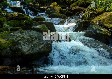 A waterfall as it cascades down the hillside towards Lynmouth, Devon, UK and out to sea Stock Photo