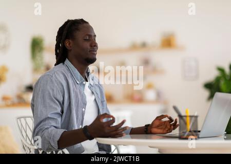 Zen Concept. Portrait Of Young Black Male Sitting At Desk And Meditating Stock Photo