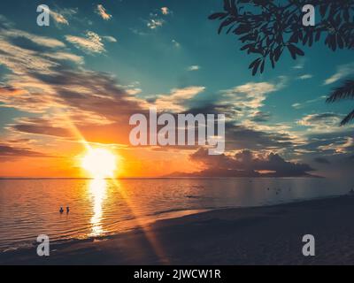 Bright orange sun sunset over sea coast. Sandy beach and cloudy sky. Beautiful nature landscape. Impressive colorful seascape. Amazing natural background. Popular touristic destination Stock Photo