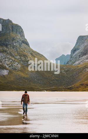 Man traveling in Norway hiking outdoor active healthy lifestyle walking on sandy Horseid beach Lofoten islands summer vacations Stock Photo