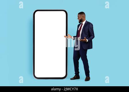 Amazing Offer. Surprised Black Businessman In Suit Looking At Big Blank Smartphone Stock Photo