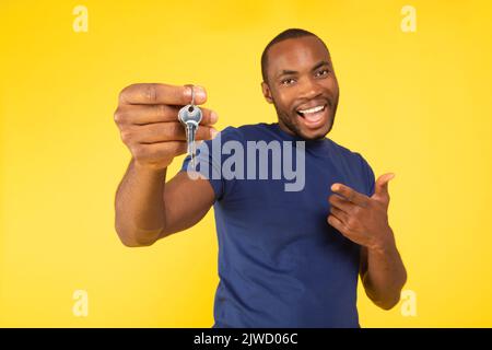 Cheerful Black Man Holding New House Keys Over Yellow Background Stock Photo