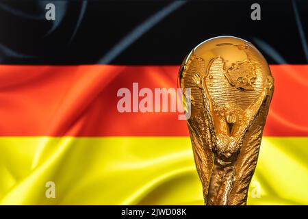 Doha, Qatar - September 4, 2022: FIFA World Cup trophy against the background of Germany flag. Stock Photo