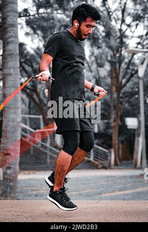 Asian sportsman training with jumping rope in the park. Fitness concept. Stock Photo