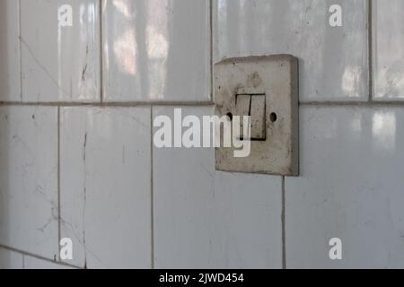 Dirty light switch on tiled wall close up, urban exploration Stock Photo