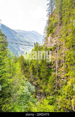 Simple suspension footbridge over mountain valley Stock Photo