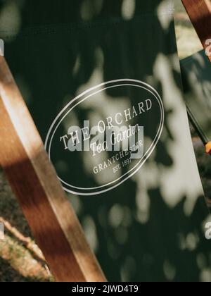 The Orchard Tea Gardens outdoor seating with logo and dappled light in Grantchester Cambridge Cambridgeshire England UK Stock Photo