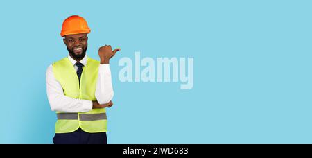 Nice Offer. Smiling Black Civil Engineer Pointing Aside At Copy Space Stock Photo